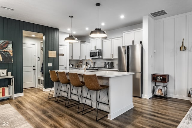 kitchen with an island with sink, visible vents, appliances with stainless steel finishes, and light countertops