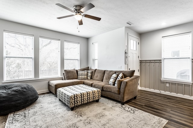 living area with visible vents, a textured ceiling, baseboards, ceiling fan, and dark wood-style flooring