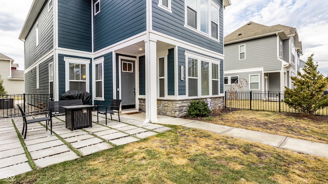 back of house featuring stone siding, a patio, and fence