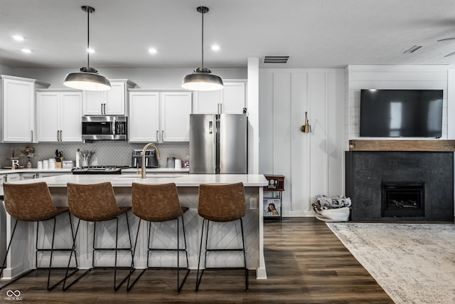 kitchen featuring visible vents, dark wood finished floors, light countertops, appliances with stainless steel finishes, and backsplash