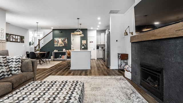 living area featuring visible vents, recessed lighting, a fireplace, dark wood-type flooring, and a notable chandelier