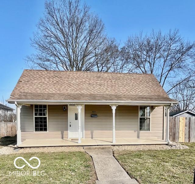 view of front of house with a porch, a front lawn, roof with shingles, and fence