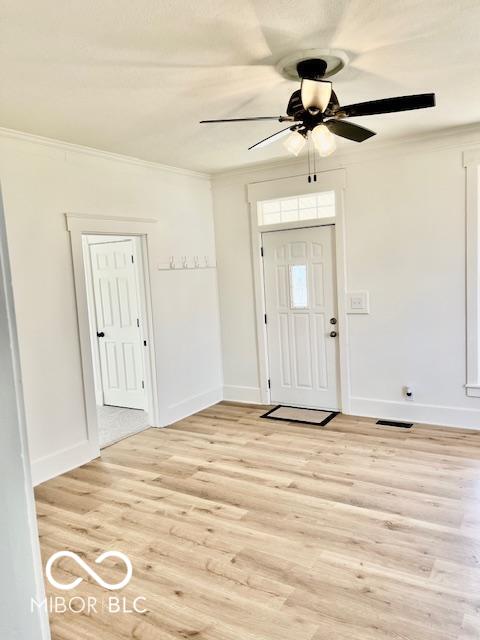 entryway with ceiling fan, baseboards, light wood-type flooring, and ornamental molding