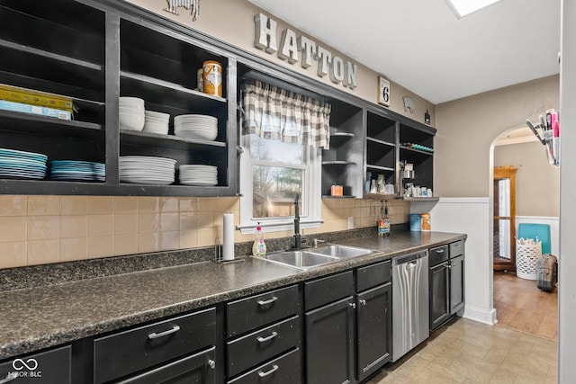 kitchen with dishwasher, open shelves, arched walkways, and a sink