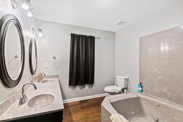 full bathroom featuring a whirlpool tub, toilet, wood finished floors, and a sink