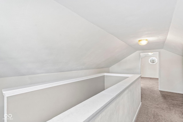 hallway featuring lofted ceiling, an upstairs landing, and light colored carpet