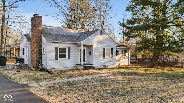 bungalow-style house with a shingled roof, a front lawn, fence, and a chimney