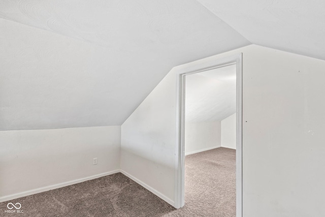 additional living space with baseboards, lofted ceiling, and carpet flooring