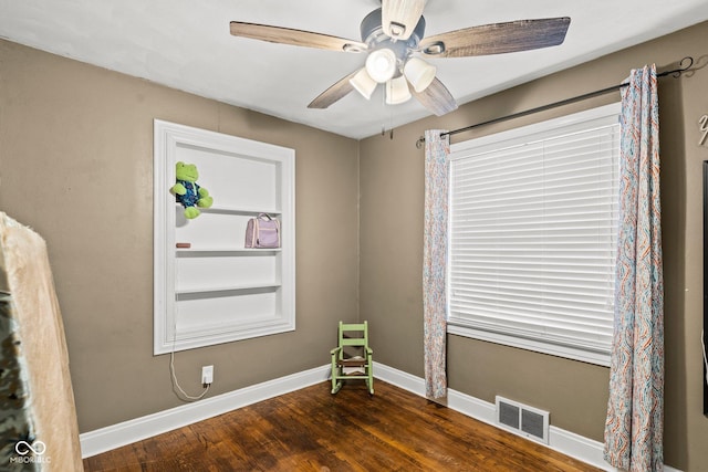 empty room with visible vents, baseboards, a ceiling fan, and dark wood-style flooring