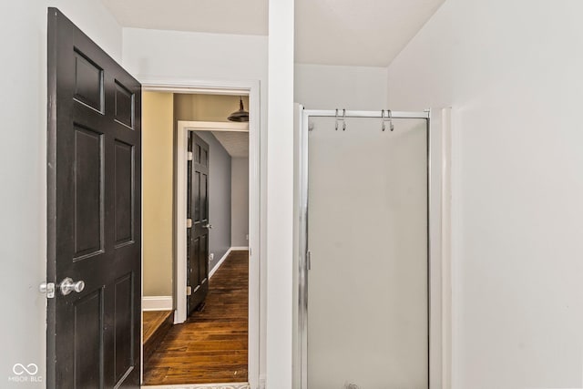 bathroom featuring baseboards, wood finished floors, and a shower stall