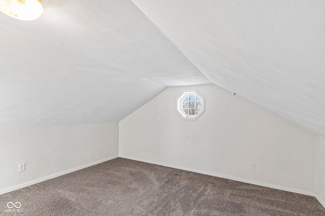 additional living space featuring baseboards, lofted ceiling, and carpet floors