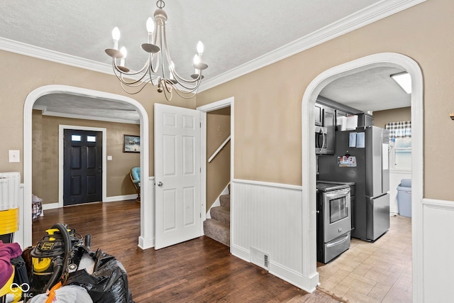 entrance foyer featuring visible vents, a wainscoted wall, wood finished floors, arched walkways, and crown molding