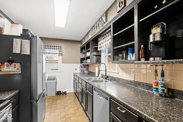 kitchen with a sink, open shelves, tasteful backsplash, dark countertops, and appliances with stainless steel finishes