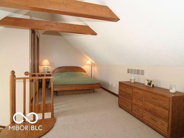 bedroom featuring visible vents, baseboards, light colored carpet, and vaulted ceiling with beams