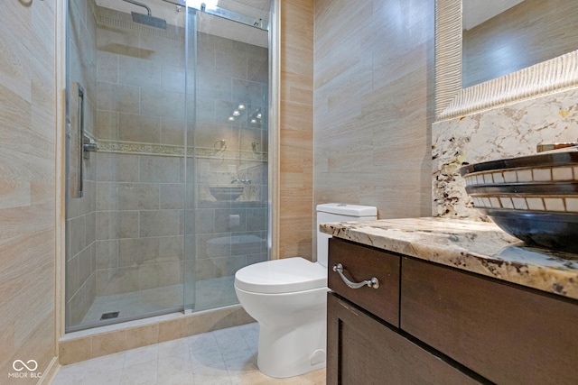 full bath with vanity, a shower stall, tile walls, toilet, and tile patterned floors