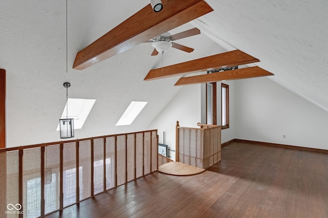 additional living space featuring baseboards, lofted ceiling with skylight, wood finished floors, a textured ceiling, and a ceiling fan