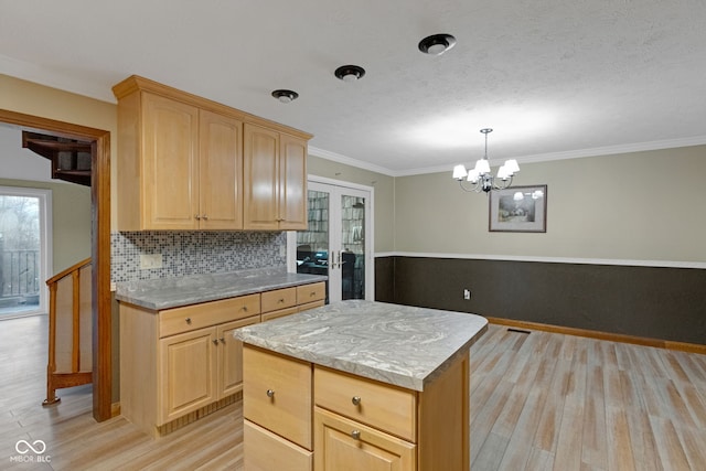 kitchen featuring light brown cabinets, backsplash, a kitchen island, light wood-style floors, and light countertops