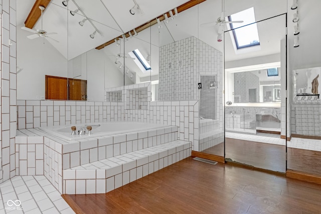 bathroom with ceiling fan, a garden tub, and a skylight