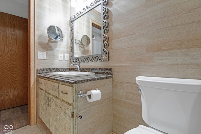 half bathroom with toilet, vanity, and tile patterned flooring