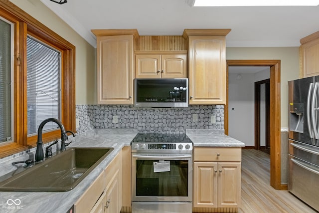 kitchen featuring a sink, stainless steel appliances, tasteful backsplash, and light brown cabinetry