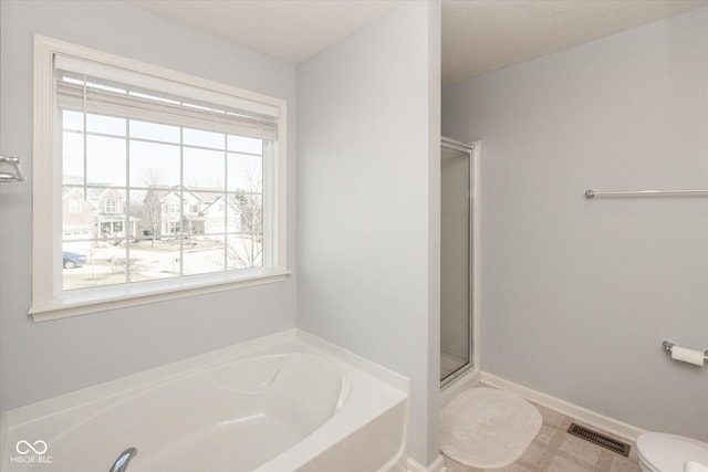 bathroom with baseboards, visible vents, a shower stall, a garden tub, and toilet