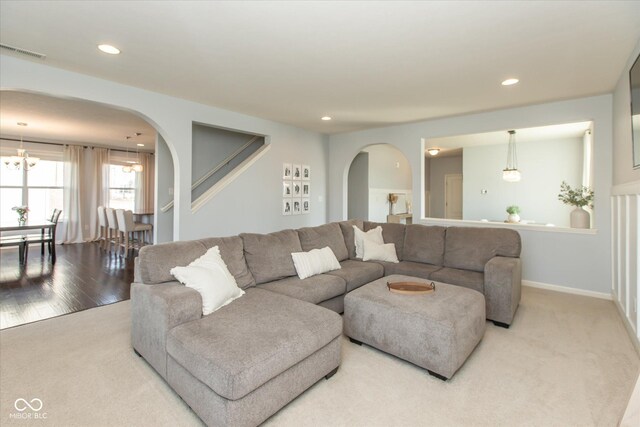 carpeted living room with arched walkways, visible vents, and recessed lighting