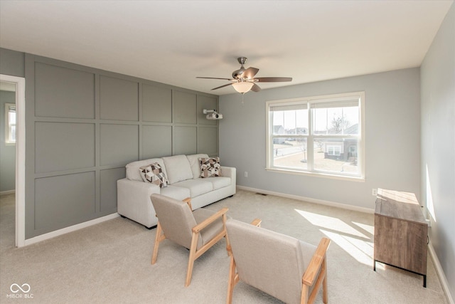 living area with a ceiling fan, visible vents, baseboards, light carpet, and a decorative wall