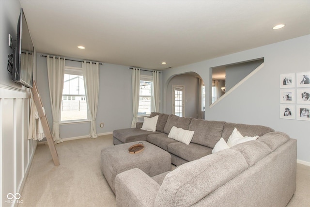 living area featuring recessed lighting, light colored carpet, arched walkways, and baseboards