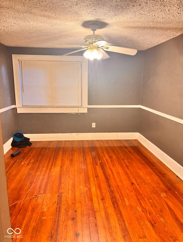 spare room featuring hardwood / wood-style floors, a ceiling fan, baseboards, and a textured ceiling