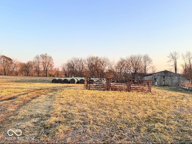 yard at dusk featuring an outbuilding, a barn, and a rural view