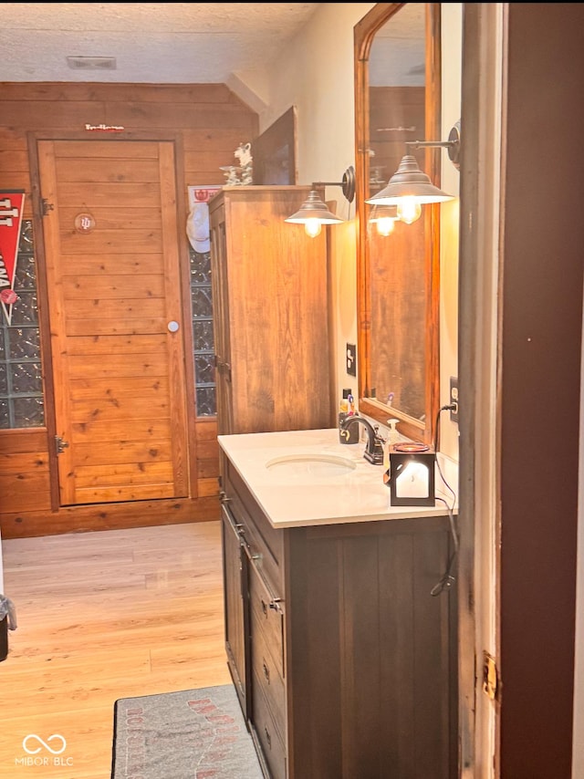 bathroom featuring vanity, wooden walls, and wood finished floors