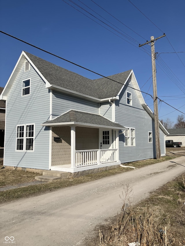 view of front of house with a porch, dirt driveway, and a shingled roof