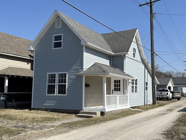 traditional-style home featuring covered porch and a shingled roof