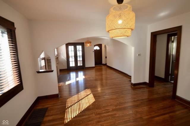 entryway featuring arched walkways, visible vents, baseboards, and wood finished floors