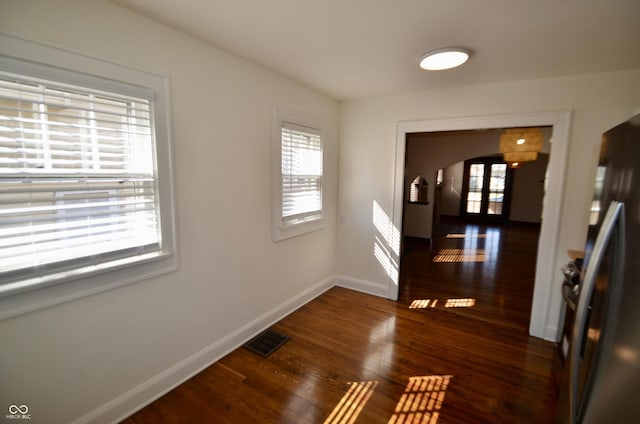 hallway featuring a wealth of natural light, visible vents, baseboards, and wood finished floors