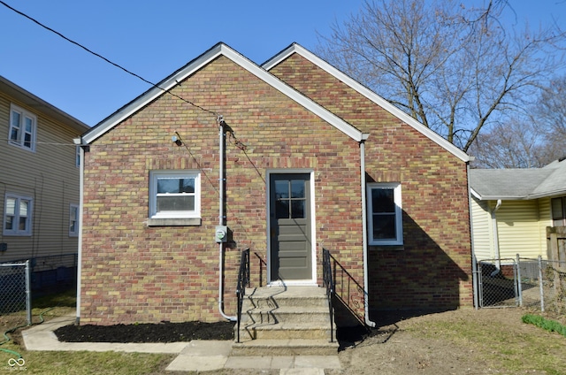 back of property featuring fence, brick siding, and a gate