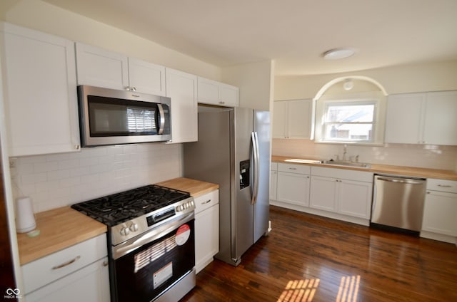 kitchen featuring dark wood-style floors, stainless steel appliances, decorative backsplash, white cabinetry, and butcher block counters