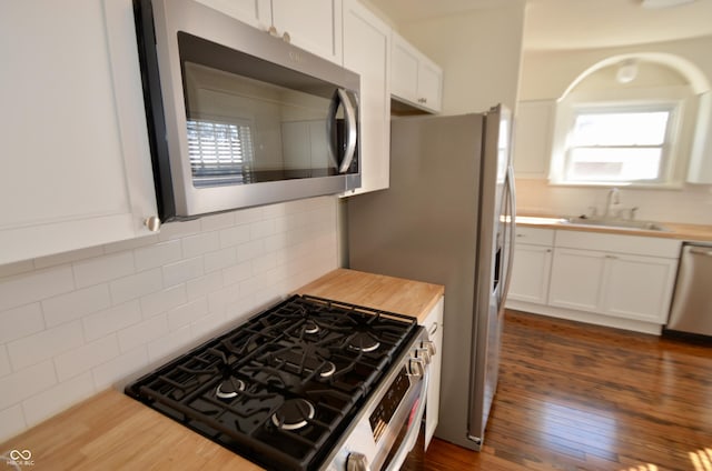 kitchen featuring a sink, white cabinetry, appliances with stainless steel finishes, decorative backsplash, and dark wood-style flooring