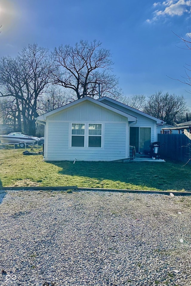 view of side of home with fence, board and batten siding, and a lawn