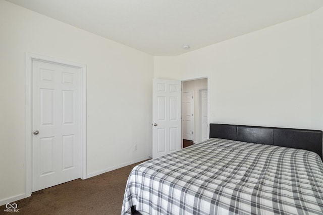 bedroom with dark colored carpet and baseboards