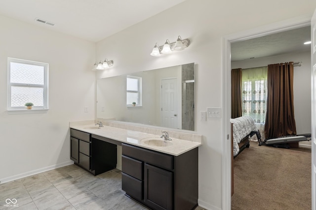 ensuite bathroom featuring a healthy amount of sunlight, connected bathroom, and a sink