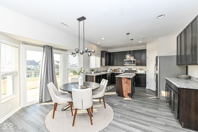 dining area with light wood-style flooring, recessed lighting, visible vents, and a chandelier