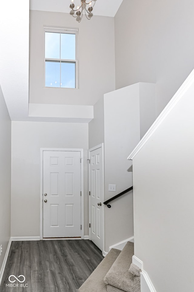 entrance foyer with wood finished floors, a towering ceiling, stairway, baseboards, and a chandelier