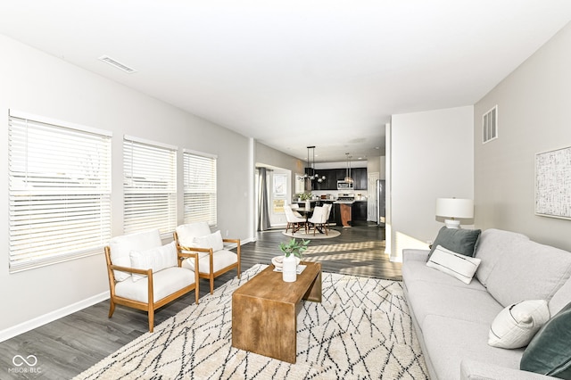 living area featuring visible vents, baseboards, and wood finished floors