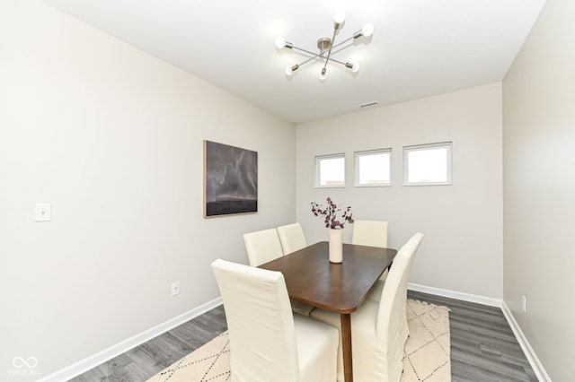 dining room with a notable chandelier, visible vents, baseboards, and wood finished floors