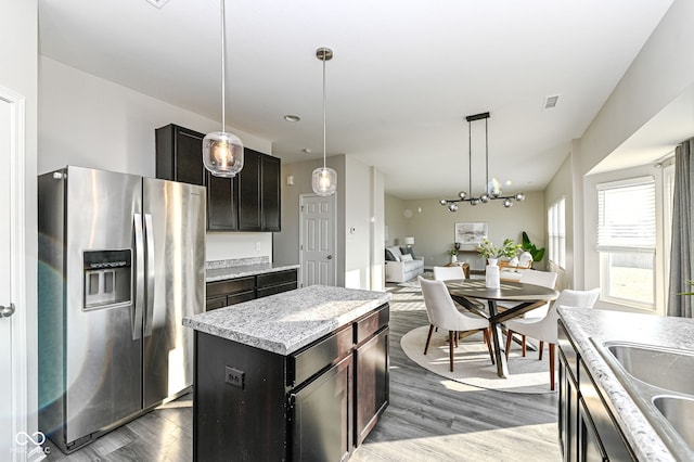 kitchen featuring visible vents, dark wood-type flooring, stainless steel fridge with ice dispenser, hanging light fixtures, and a sink