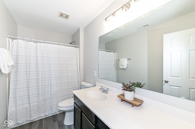 full bath featuring visible vents, toilet, vanity, and wood finished floors