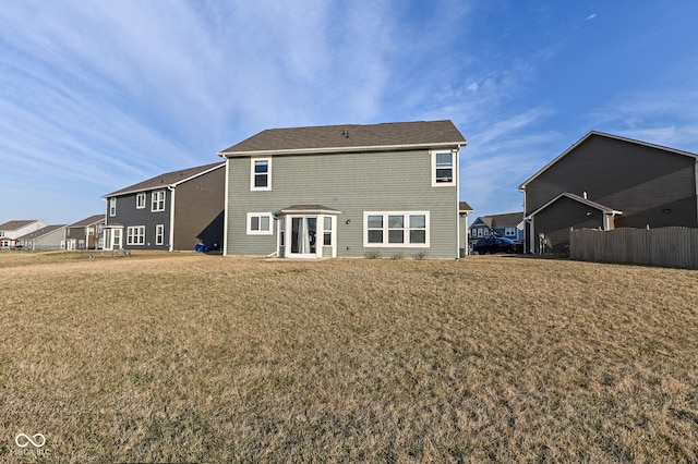 rear view of house with a lawn and fence