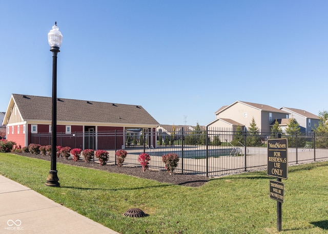 view of property's community with a pool, fence, and a lawn