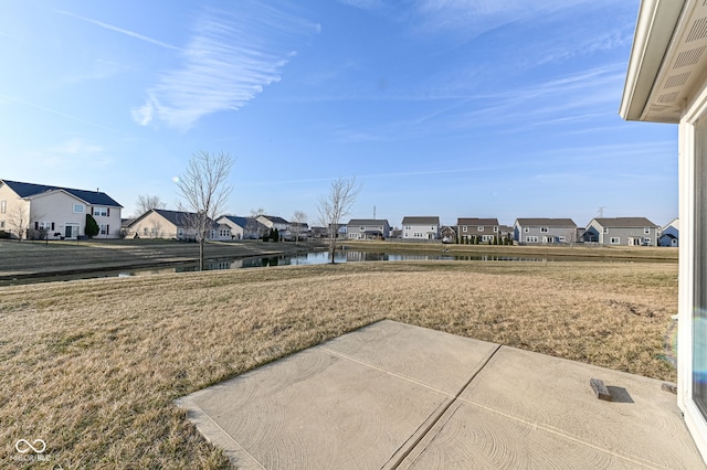 view of yard featuring a patio area, a residential view, and a water view